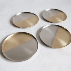 four silver and gold plates on a white surface