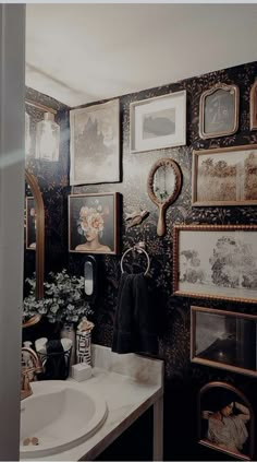 a bathroom with black and white wallpaper has pictures on the walls, framed photos above it