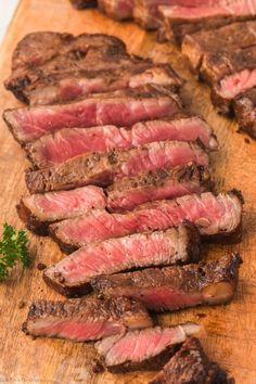 steak sliced up and ready to be served on a wooden cutting board with parsley