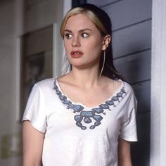 a woman standing in front of a door with her hand on her hip and looking off to the side