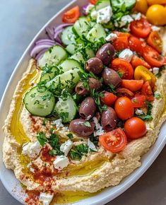 hummus with olives, tomatoes, cucumbers and other vegetables on top