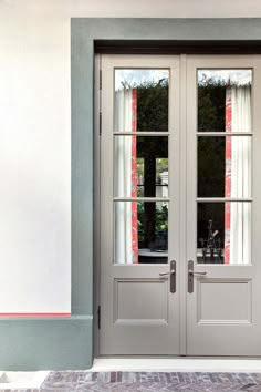 two double doors with sidelights and curtains in front of a white wall, on the outside of a house