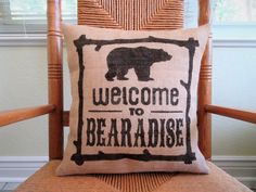 a welcome to bearadise pillow sitting on top of a wooden chair in front of a window