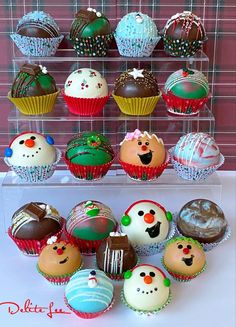 there are many cupcakes on display in the glass case with frosting and decorations