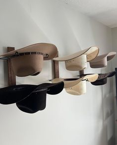 several hats hanging from hooks on a wall