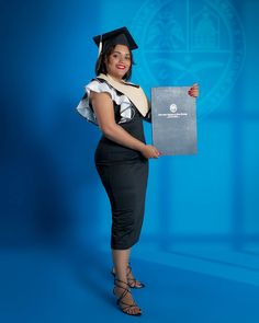 a woman in a graduation gown is holding a diploma and posing for the camera on a blue background