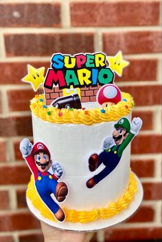 a hand holding up a super mario birthday cake