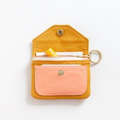 an orange and pink pouch with a toothbrush in it on a white surface next to a gold keychain