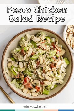 a bowl filled with chicken salad next to a fork and spoon on a white table