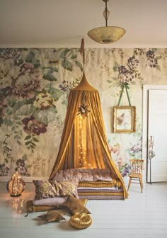 a canopy bed sitting in the middle of a living room next to a wall with flowers on it