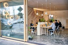 people sitting at tables in front of a window with the reflection of cars on it