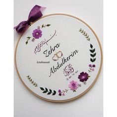 a cross stitch pattern with the names of two different countries and flowers on it, along with a purple ribbon