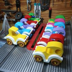 colorful wooden toy cars are lined up on a conveyor belt in a shop or workshop