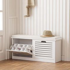 a white bench sitting next to a window with a hat on it's head