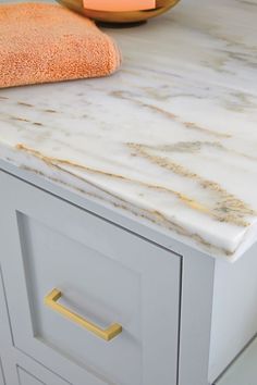 a marble counter top in a bathroom with gold handles and knobs on the drawers