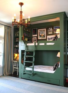 a green bunk bed in a room with pictures on the wall and a chandelier