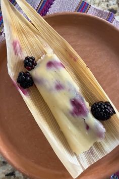 A partially unwrapped tamale with a blackberry-filled masa sits on a corn husk. Three fresh blackberries are placed on the tamale, which rests on a clay plate with a colorful woven cloth in the background. Fruit Tamales, Cream Cheese Tamales, Tamale Recipes, Cheese Tamales, Homemade Tamales Recipe, Sweet Tamales, Tamales Recipe, Homemade Tamales, Mexican Sweets