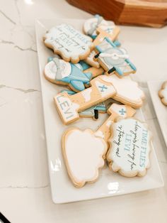 some cookies are on a white plate and one is decorated with blue and white icing