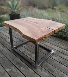 a wooden table sitting on top of a wooden deck next to a potted plant