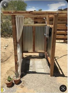 an outdoor shower made out of pallets and wooden posts with curtains on the side