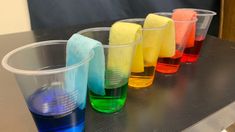 the cups are lined up with different colored liquids in them, and one is empty