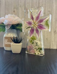 a cross made out of glass sitting on top of a table next to a potted plant