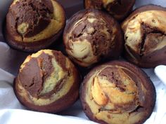 several chocolate muffins sitting in a basket on top of a white cloth covered table