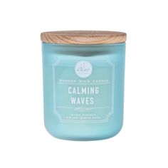 a candle that says calming waves in front of a white background with a wooden lid