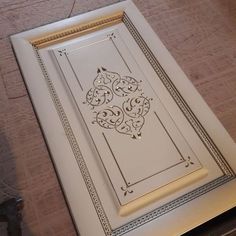 a close up of a white door on a wooden floor with an ornate design in the middle