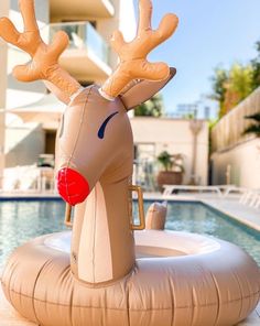 an inflatable reindeer float sitting on top of a pool next to a building