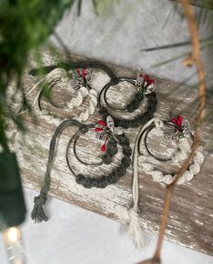 three bracelets with red flowers are sitting on a piece of wood next to a potted plant