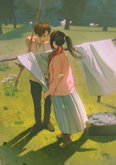 two people standing in the grass with clothes hanging out to dry