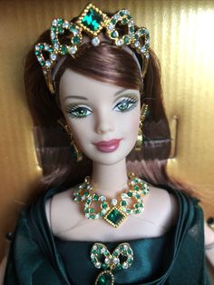 a doll wearing a green dress and tiara with jewels on it's head