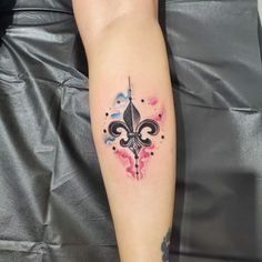 a woman's arm with a watercolor fleur de lis tattoo on it