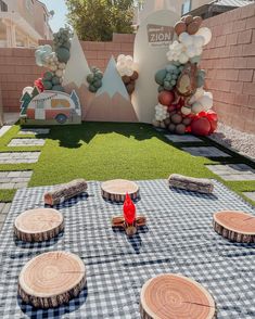 an outdoor picnic area with wood slices and balloons