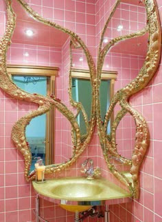 a bathroom with pink tiles and gold accents on the walls, along with a sink