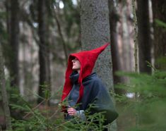 a man wearing a red hood in the woods