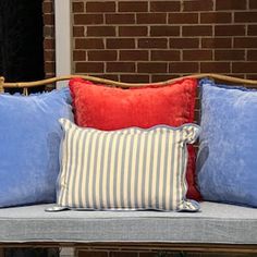 three pillows are sitting on a bench in front of a brick wall and window sill