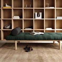 a green bench sitting in front of a bookshelf filled with shelves and shoes