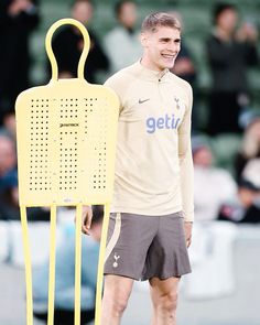 a man standing next to a giant yellow object on top of a soccer ball field