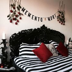 a black and white striped bed with red pillows, candles and decorations on the wall