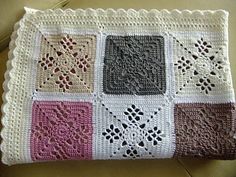 a crocheted blanket with different colors and designs on the front, sitting on top of a couch