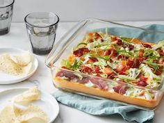 a glass casserole dish filled with salad and tortilla chips on a table