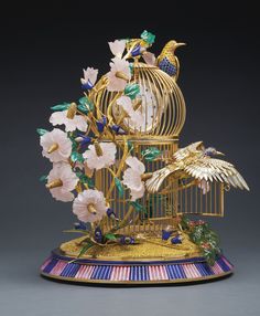 a golden birdcage with flowers and birds in it