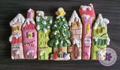 decorated cookies are arranged in the shape of houses and trees on a wooden table top