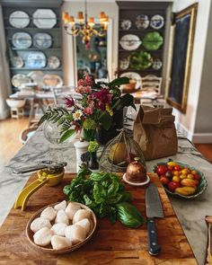 a wooden table topped with lots of fresh vegetables and fruits next to a knife on top of a cutting board