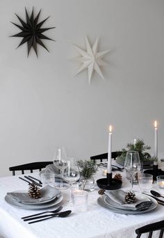 a dining table set with place settings and candles