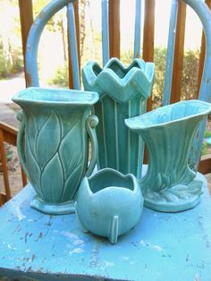 three green vases sitting on top of a blue chair