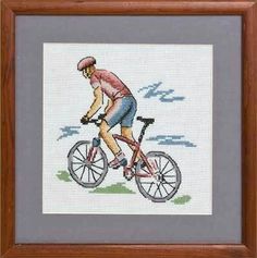 a cross stitch picture of a man riding a bike