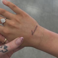 a woman's hand with a small diamond ring on her left wrist that says love